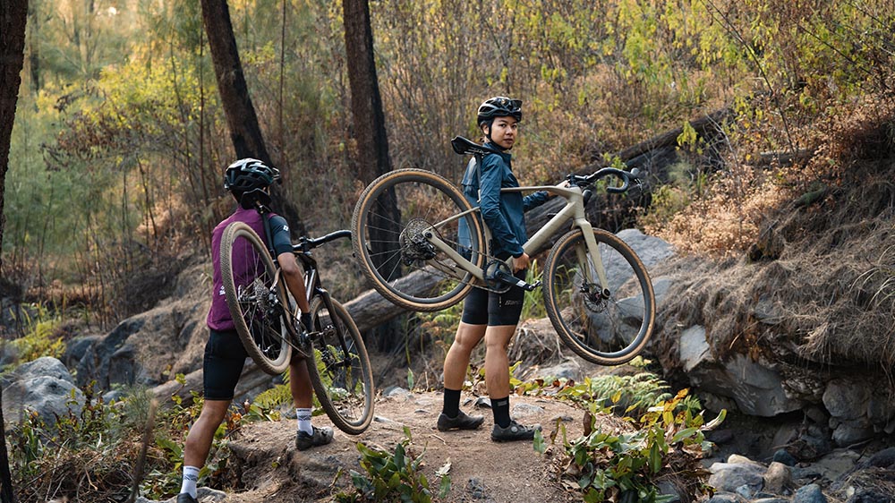 Cyclist menuntun sepeda gravel melewati sungai