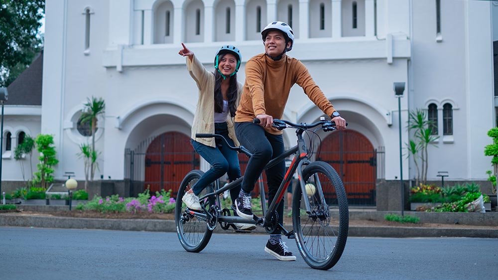 Two people riding a tandem bicycle together during a weekend outing.