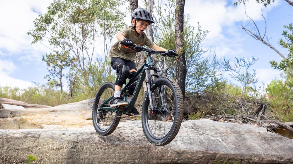 Child wearing a helmet while riding a junior mountain bike