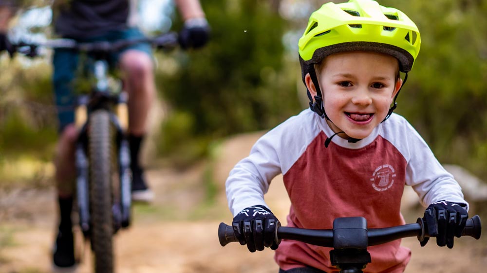 Kid suiting up with a helmet and pads before a bike ride