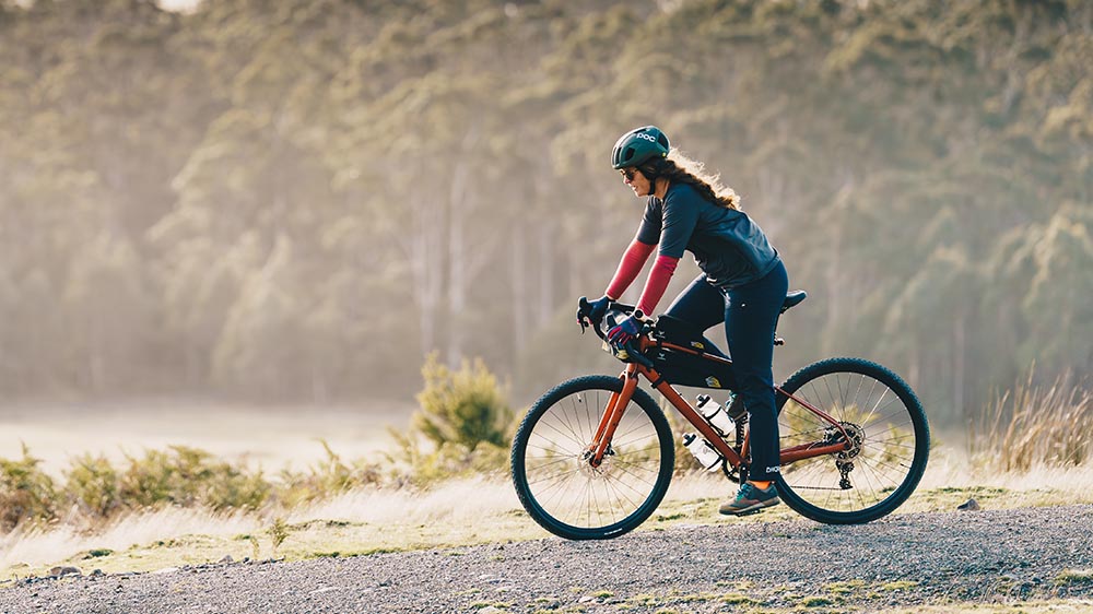 Cyclist navigating a scenic trail on a gravel bike during a bikepacking trip